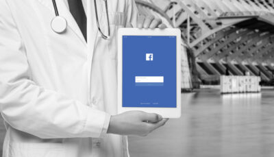 Un dottore mostra un tablet con la pagina di login di Facebook
