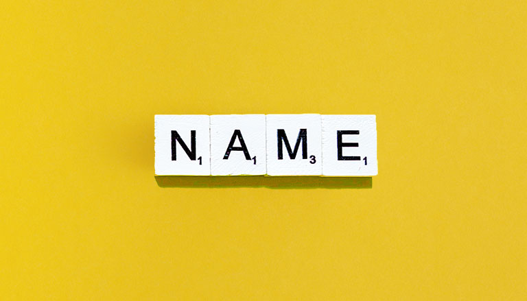 4 dadi di colore bianco su fondo giallo contengono 4 lettere nere che compongono la scritta "NAME"