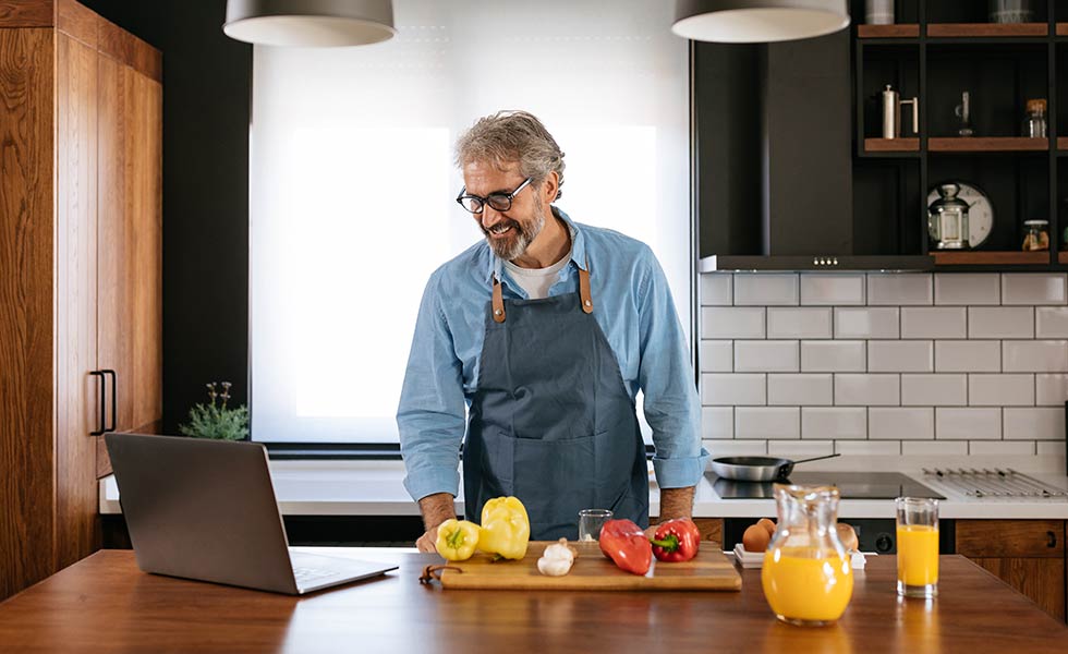 In questa immagine, una uomo in cucina che sta leggendo una ricetta su Google