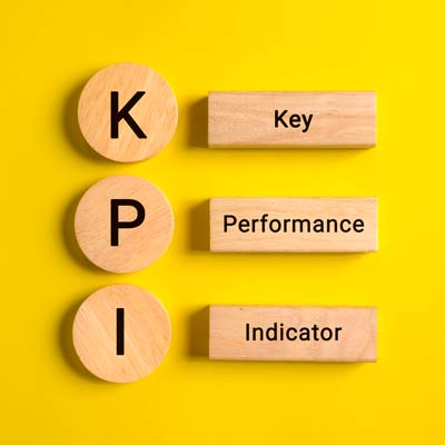 scritta KPI realizzata con 3 pedine di legno. A lato di ogni lettera la relativa spiegazione Key - Performance - Indicator