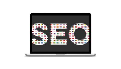scritta SEO realizzata con le bandiere delle nazioni visualizzati su un computer portatile