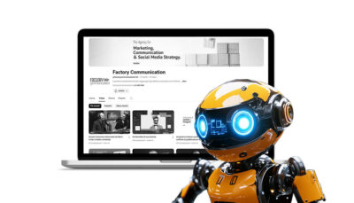 Un robot giallo davanti ad un computer portatile sul quale è visualizzato il canale YouTube di Factory Communication