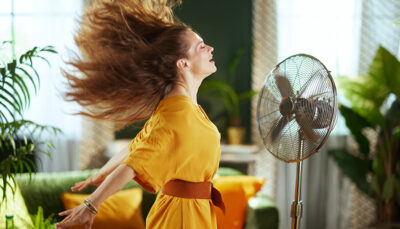 una donna vestita di arancione si rinfresca davanti ad un ventilatore