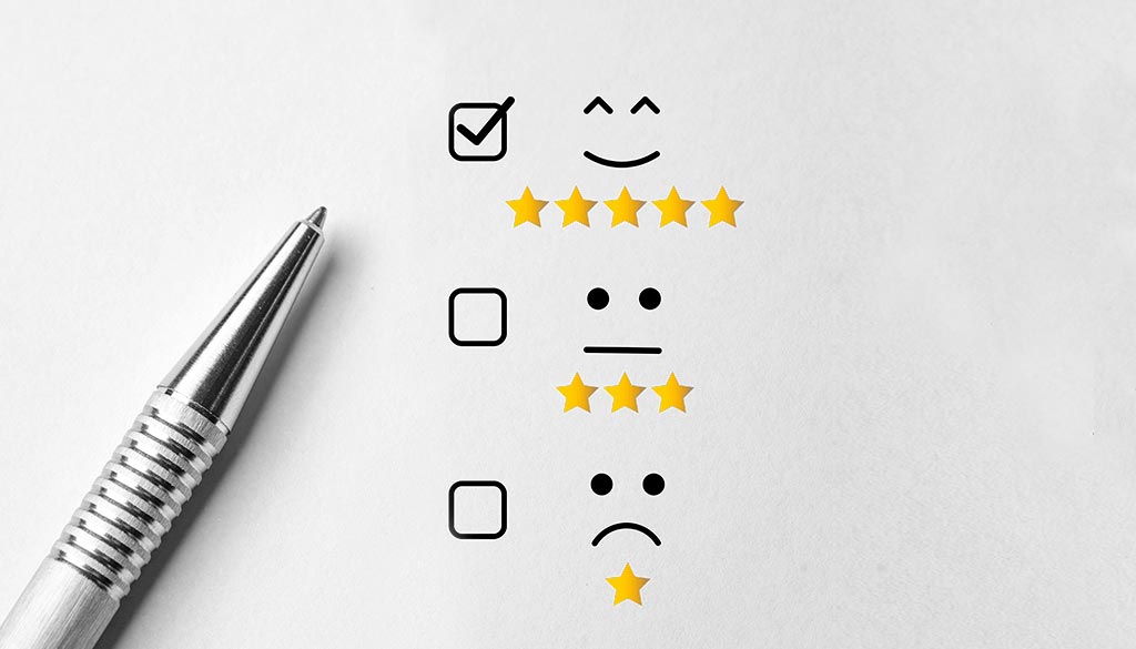 Su un foglio di carta grigio 3 selettori: uno con 5 stelle e la faccina sorridente, 1 con 3 stelle e faccina neutra ed uno con 1 stella e faccina preoccupata