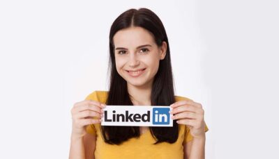 una giovane donna tiene tra le mani un cartello con riportato il logo di Linkedin