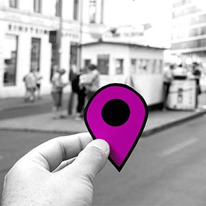 A hand holds a purple location marker.