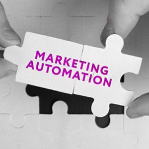 Scritta Marketing automation posizionata sopra 2 pezzi di un puzzle tenuti da 2 mani