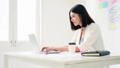 a woman writes on a laptop computer