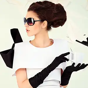 donna vestita elegantemente: abito bianco, guanti neri, occhiali neri