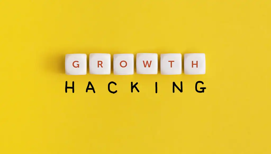 La parola growth è fatta con 6 dadi bianchi. La parola hacking è una scritta a mano di colore nero lo sfondo è giallo